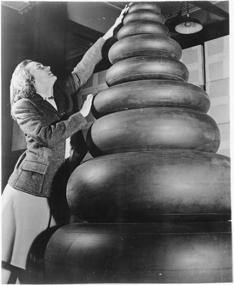 Woman_standing_next_to_a_wide_range_of_tire_sizes_required_by_military_aircraft._-_NARA_-_196199